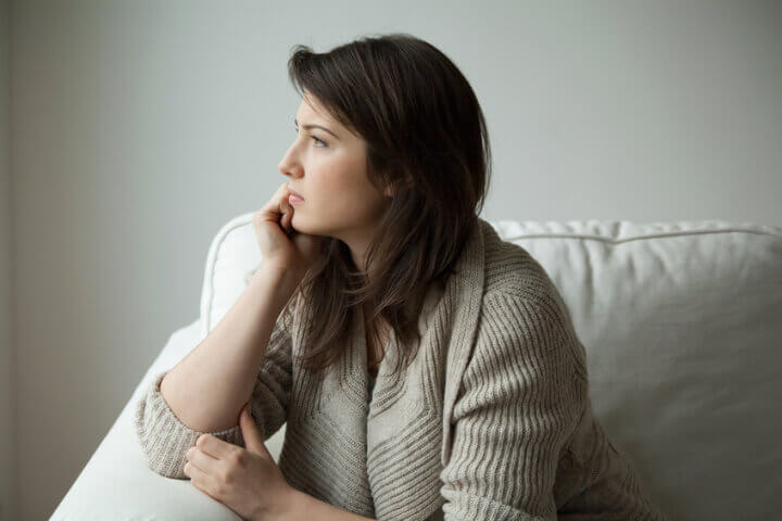 Sad girl sitting on the sofa and thinking