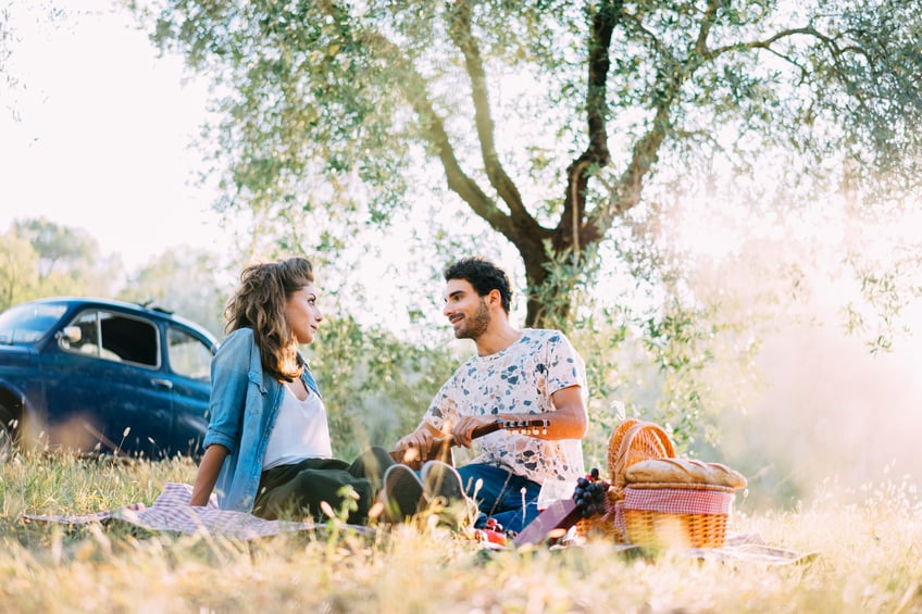 Young couple in love doing a picnic outdoors late afternoon