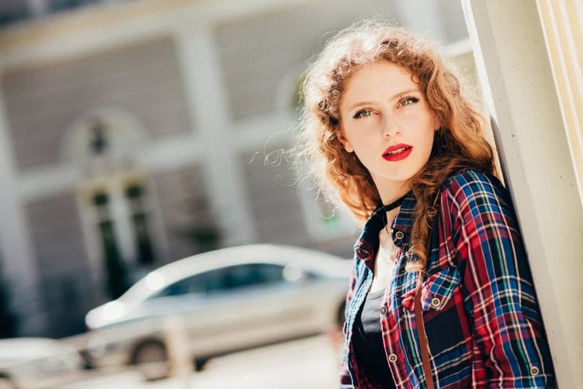 Beautiful woman with long blond curly hair in urban background.