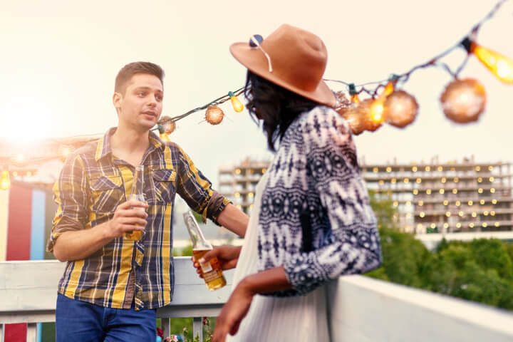 Multi-ethnic millenial couple flirting while having a drink on