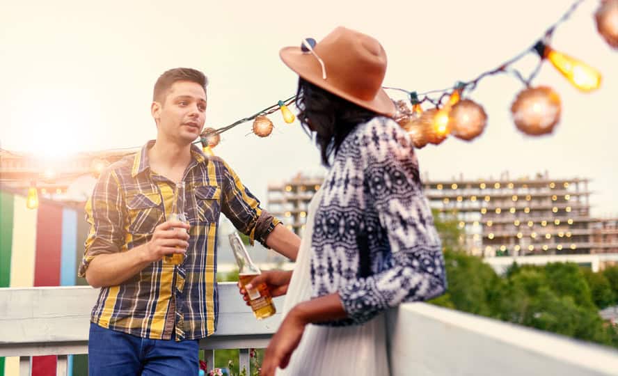 Multi-ethnic millenial couple flirting while having a drink on