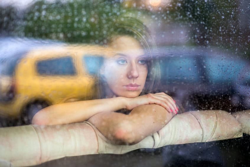 portrait of a women next to window watching the rain
