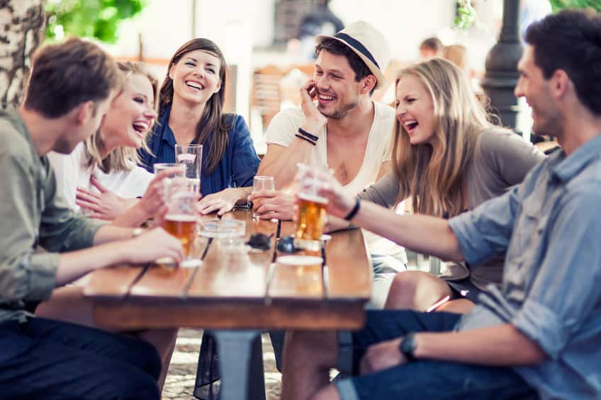Group of young cheerful people having fun drinking beer outdoors.