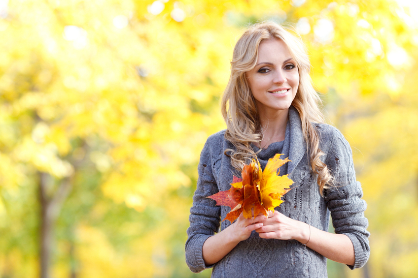 Woman holding leaves in autumn forest.