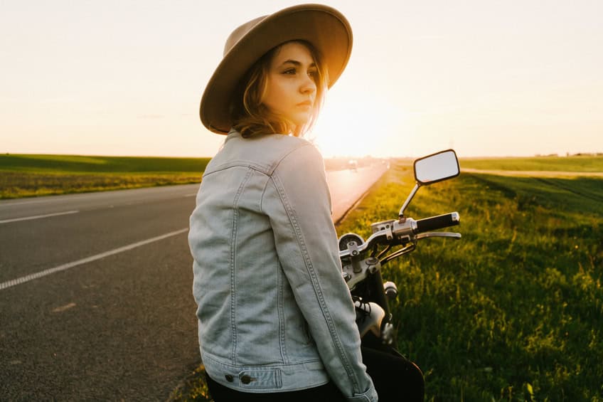 Woman on a motorcycle at sunset.
