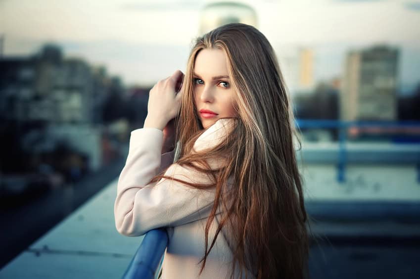 Beautiful lonely young pretty girl standing on the city roof in the sunset. Sensual evening portrait.