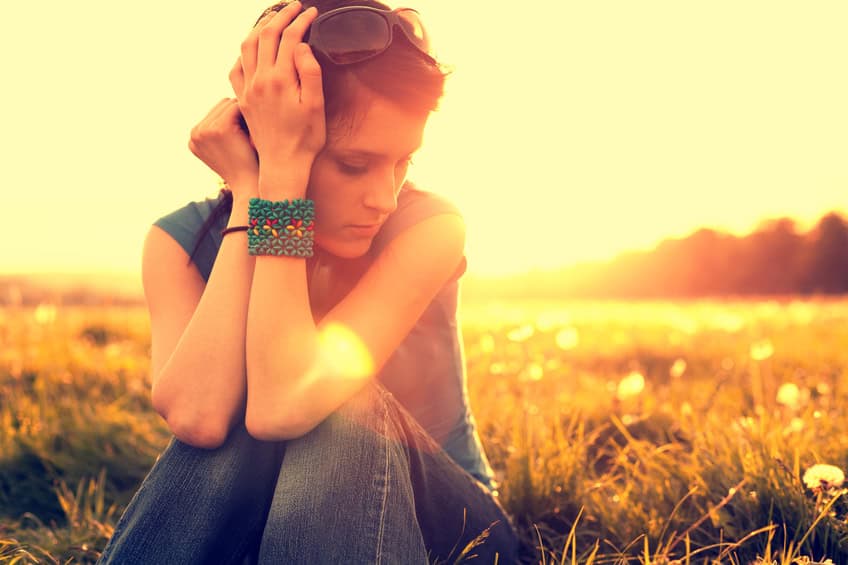 young woman sad field sunset
