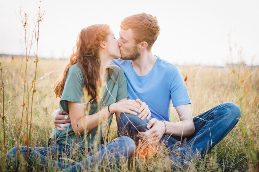 young couple kiss happy romance field