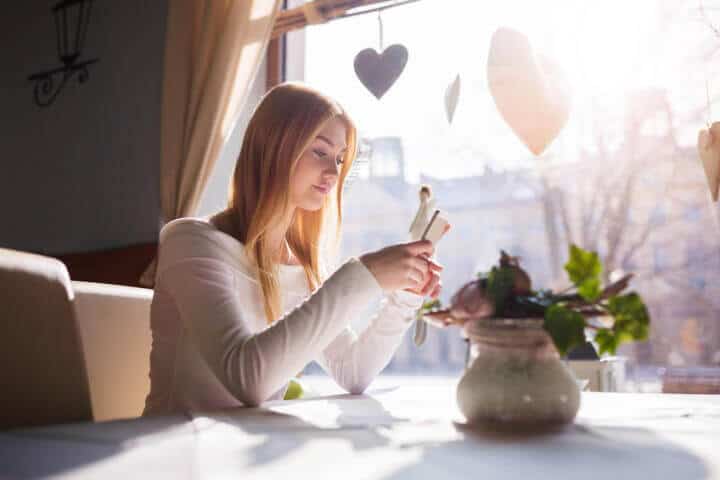 Girl texting at the cafe table