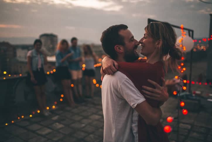 Couple of friends having a party on the rooftop of the building at sunset;