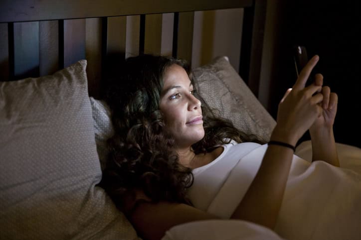 woman texting in bed