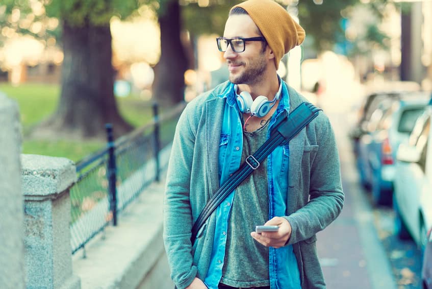 handsome man walking in the street after work ,holding his smartphone