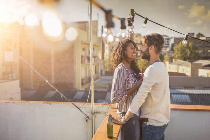Outdoor shot of young affectionate couple standing close to each other on a rooftop party