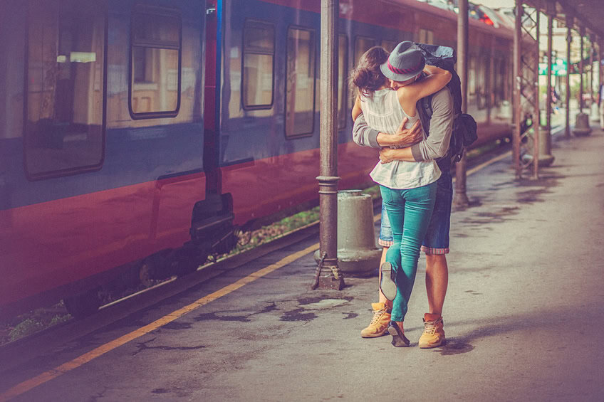 Close-up portrait of a happy woman and man at the railway platform, embracing and feeling in love. Romantic moment after a period of separation