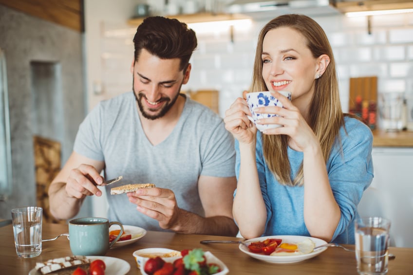 couple in their 30s having breakfast at the table with a happy smile