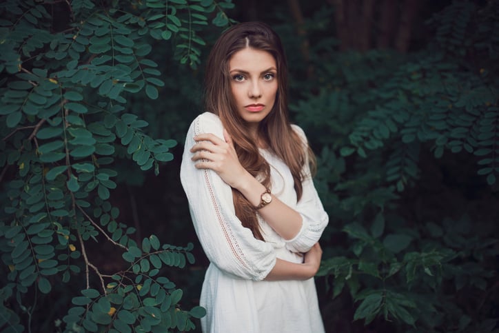 Portrait of a beautiful young woman posing in the nature among trees.