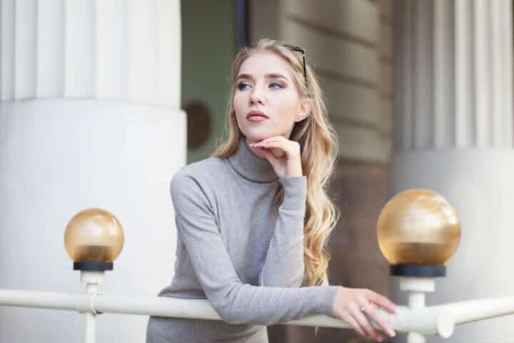 Portrait of beautiful young thinking woman looking aside. Waist up. City lifestyle.