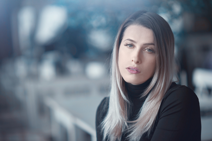 beautiful blond hair woman posing inside restaurant, looking at camera and feeling nostalgic.