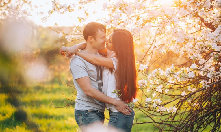 Young couple in love having fun in blossoming apple-tree garden