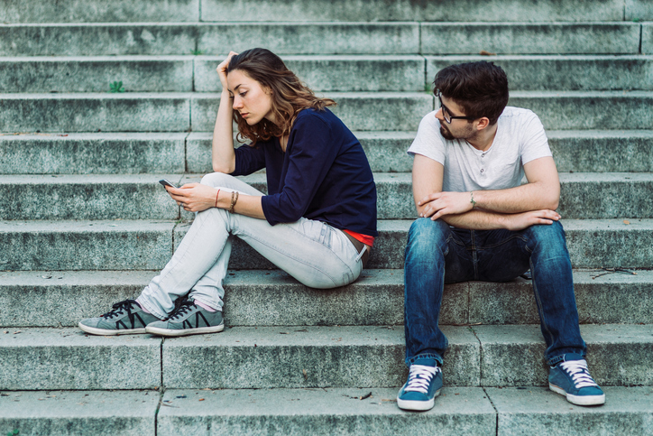Couple looking bored and gloomy sitting on the stairs outside