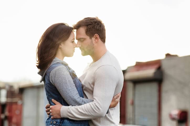 Young American couple embracing in front of sunset in an urban setting. Photographed in Brooklyn.