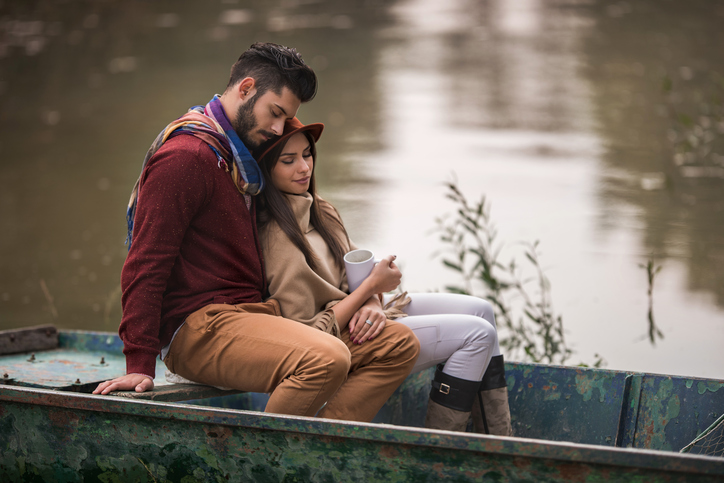 Young couple sitting in a boat during autumn day and relaxing with their eyes closed.
