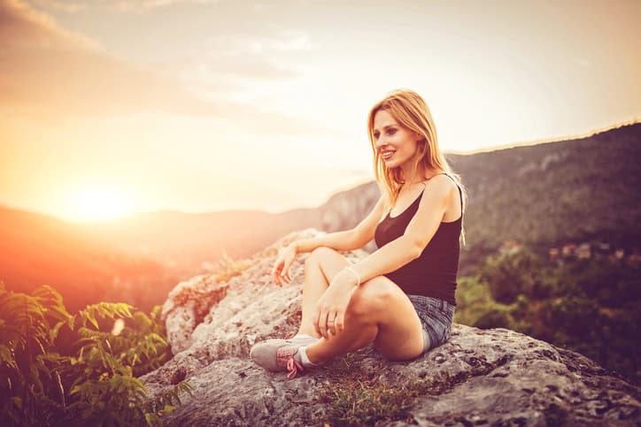 Woman sitting on a mountain rock on a beautiful summer day.
