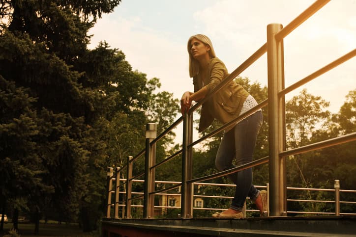 Attractive young female standing on balcony and looking to view.