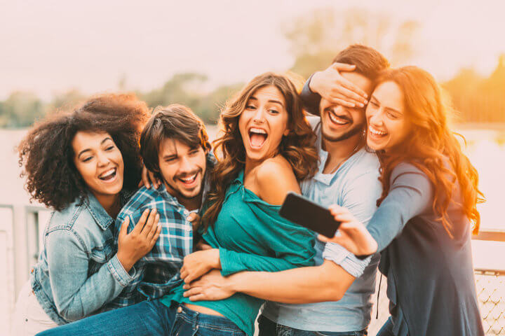Friends having fun and taking a selfie by the river.