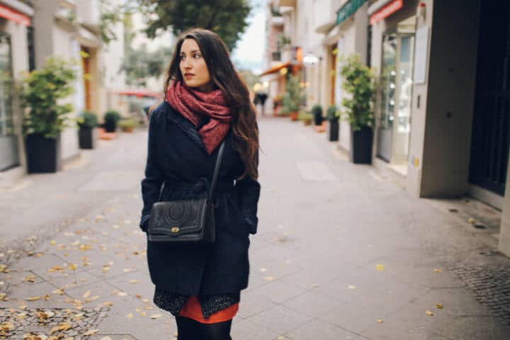 Vintage toned portrait of a young woman in Berlin, wearing a blue coat and a scarf, walking in the Schoneberg district, near Kreuzberg in the late Autumn day. Street style, casual fashion concept.