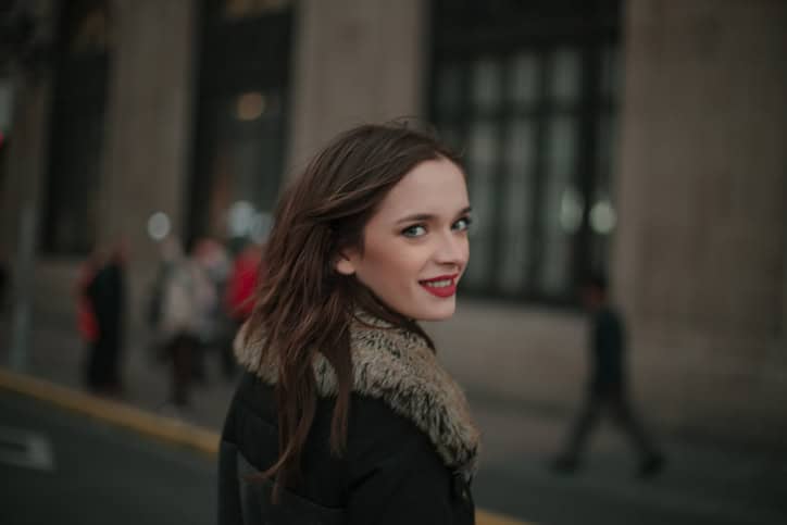 Beautiful young woman in winter jacket, walking down the city street.