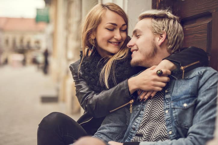 Smiling couple embracing outdoors and talking to each other.