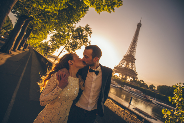 Young couple kissing in front of the Eiffel Tower.