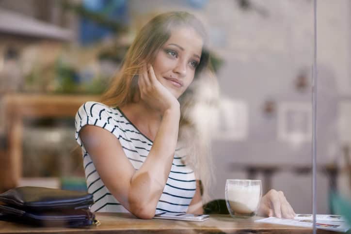 Shot of a thoughtful young woman relaxing at a coffeeshop
