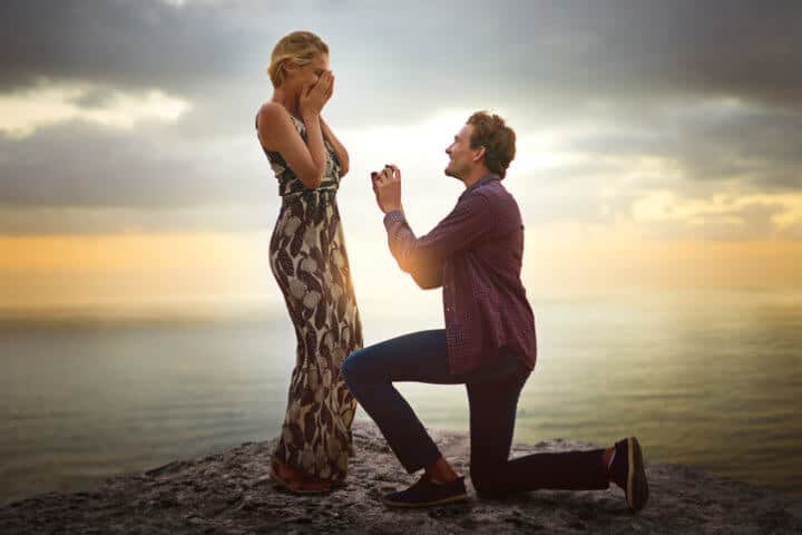 Shot of a young man proposing to his girlfriend at sunset