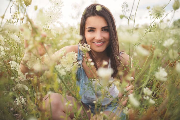 Carefree young woman enjoying a beautiful summer day in the field of wild flowers.