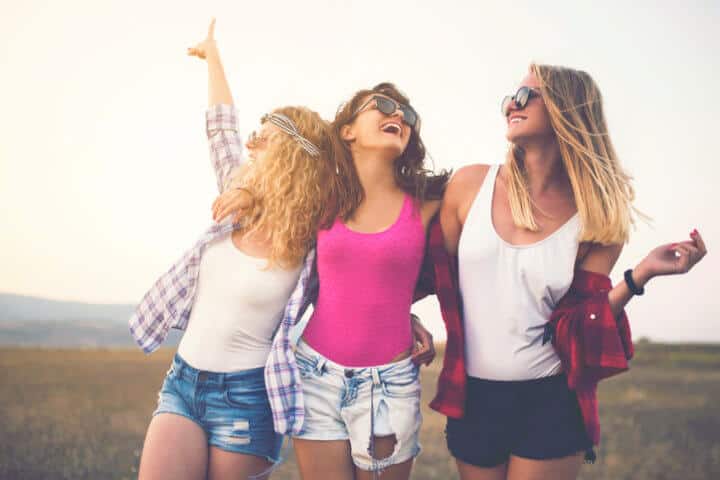 Three beautiful girls holding together, enjoying a carefree summer day outdoors.