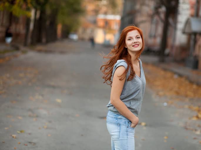Woman with red hair walking by the street