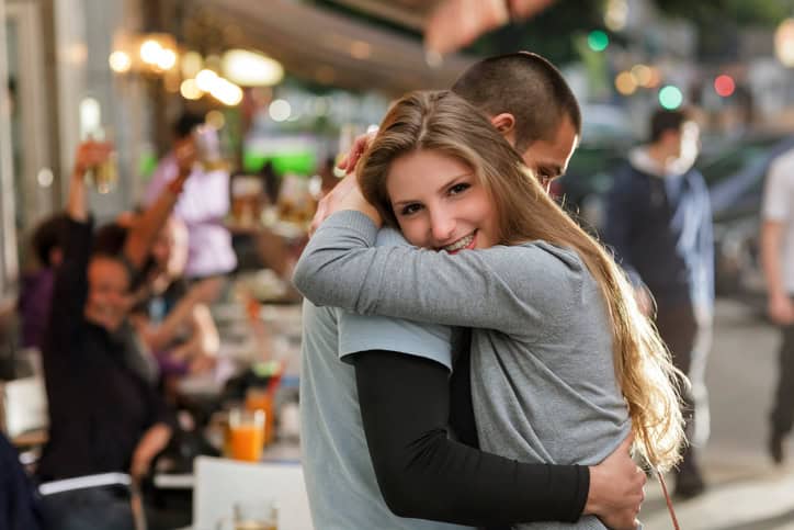 Young couple greeting hugging at an outdoor Cafe in Berlin.