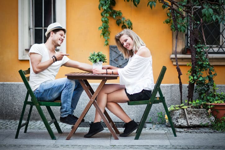 Young cheerful romantic couple sitting at the small table on the street of Wroclaw, Poland.