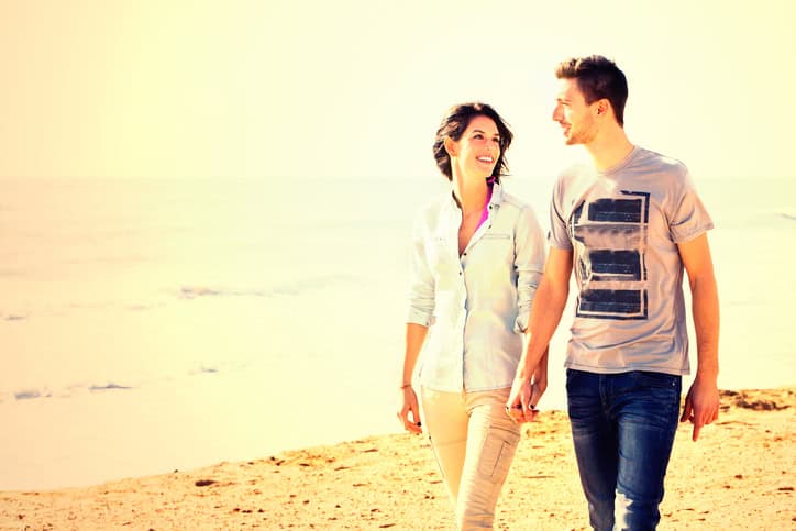 happy couple walking along the beach at sunset