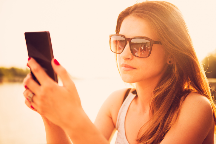 Beautiful woman with sunglasses using smart phone. Outdoor