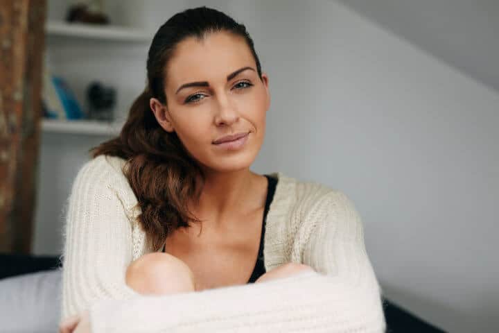 Portrait of beautiful young woman sitting at home looking at camera. Pretty relaxed woman indoors.