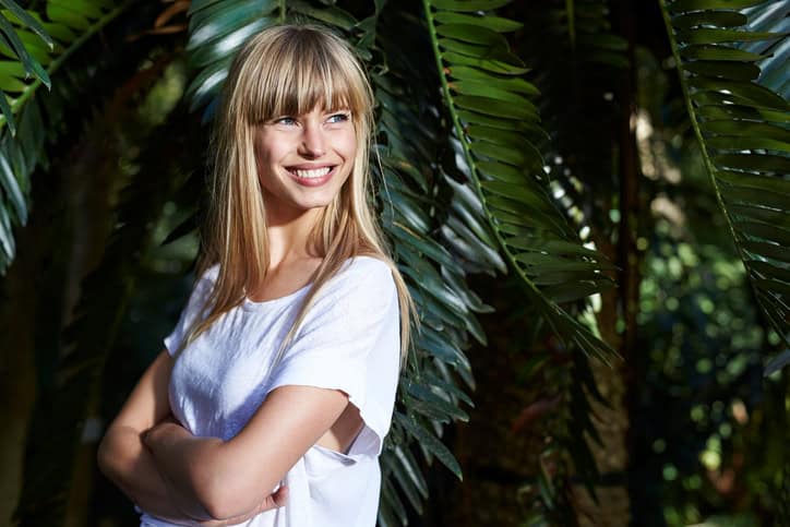 Smiling young blond beauty with arms folded