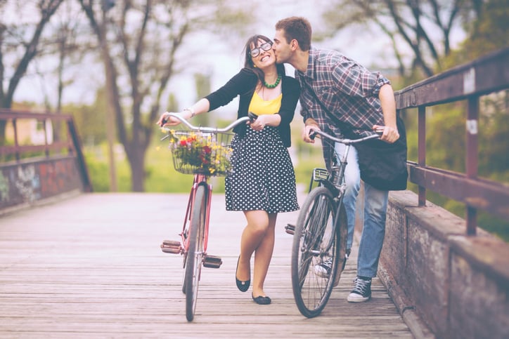 Young romantic couple on vintage bicycles in a park.