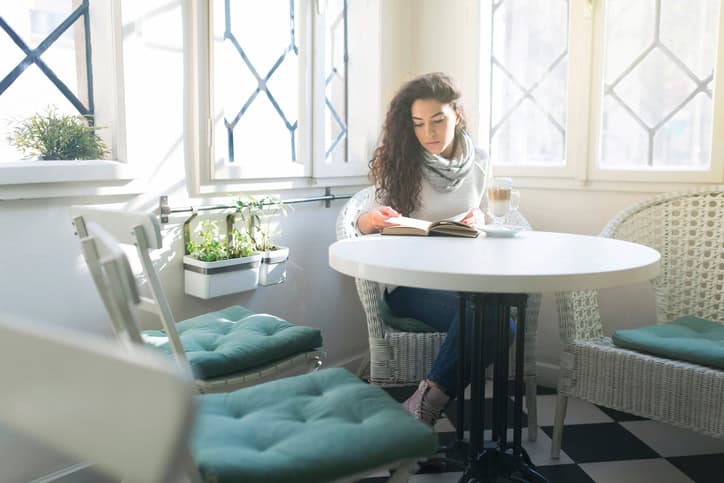 Beautiful black-haired woman reading a book, enjoying the comforts of her home.