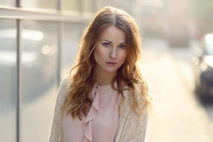 Beautiful young serious woman looking at camera in early morning sunlight outdoors