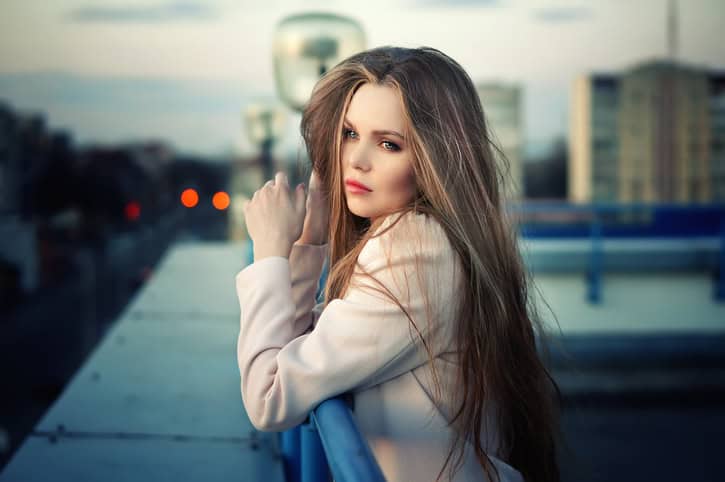 Lonely girl standing on the city roof in the sunset.