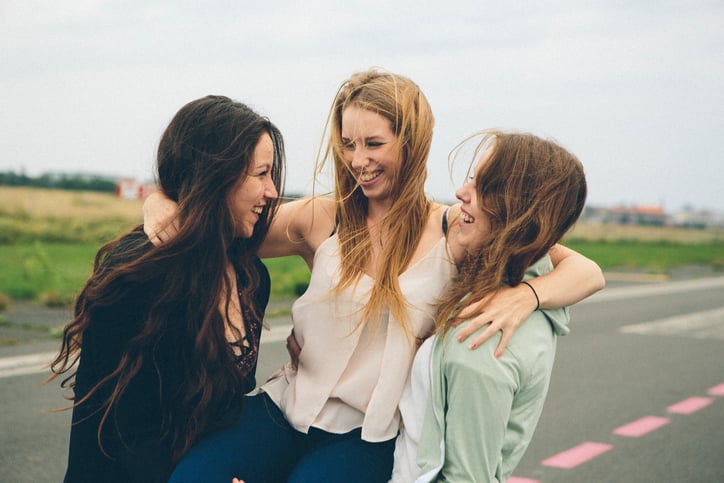 portrait: small group of laughing young women in park, carry the middle girl