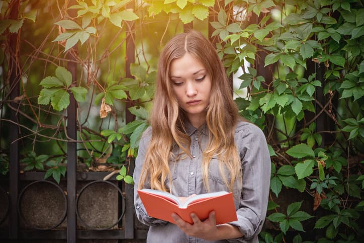 Young woman reading a. book outside.